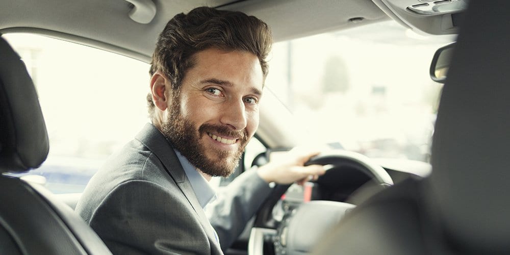 man smiling behind the wheel of a car