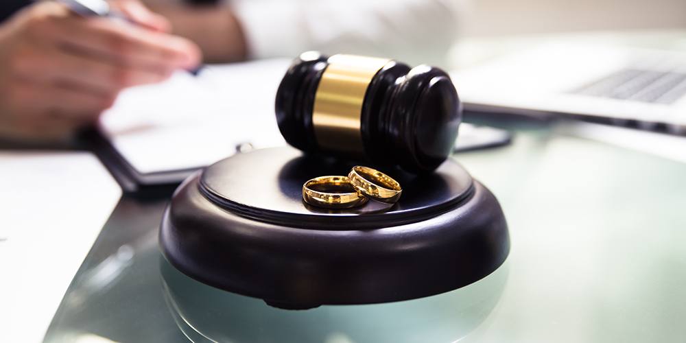 two gold wedding rings on a table next to a gavel