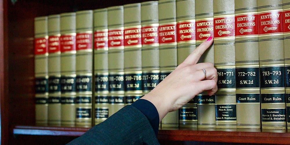 hand pointing to a book on a bookshelf
