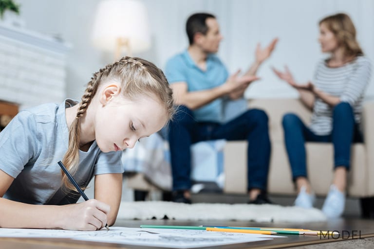 Little Girl Drawing on Floor While Parents Argue