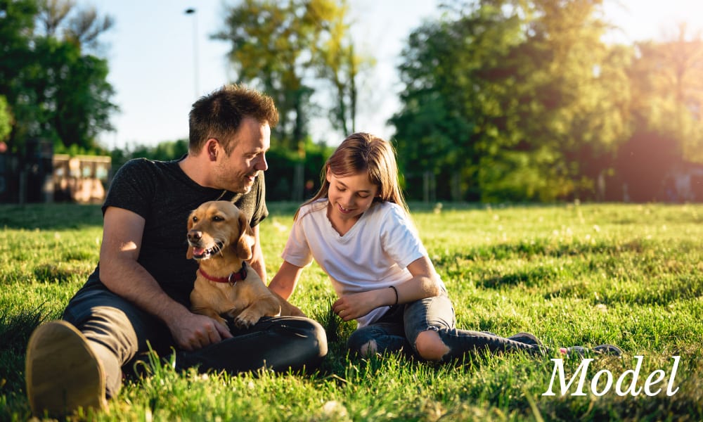 Father Daughter And Dog Sitting On Grass